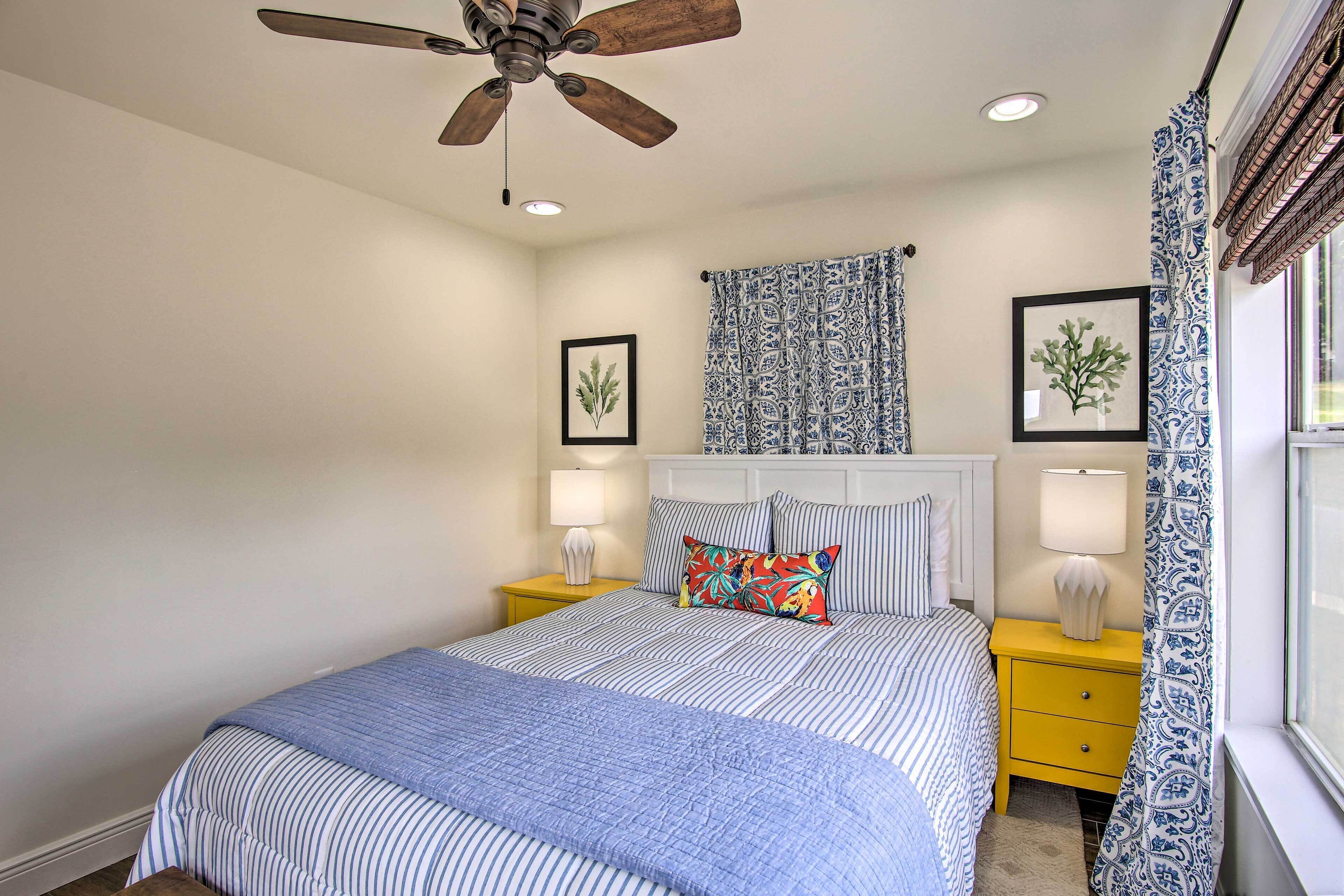 A bedroom with a bed, two nightstands, a ceiling fan, and two wall-mounted lamps.