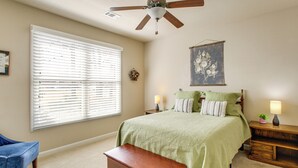 A bedroom with a bed, a nightstand, a bench, a ceiling fan, and a window with blinds.