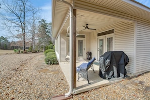 Un portico coperto con una ventola a soffitto, un barbecue e una panca.