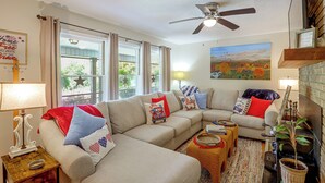 A living room with a sectional sofa, a ceiling fan, a painting, and a 'No Smoking Inside Please' sign. - Fire Pit & Game Room: Family Home in Marshall! (Weaverville)