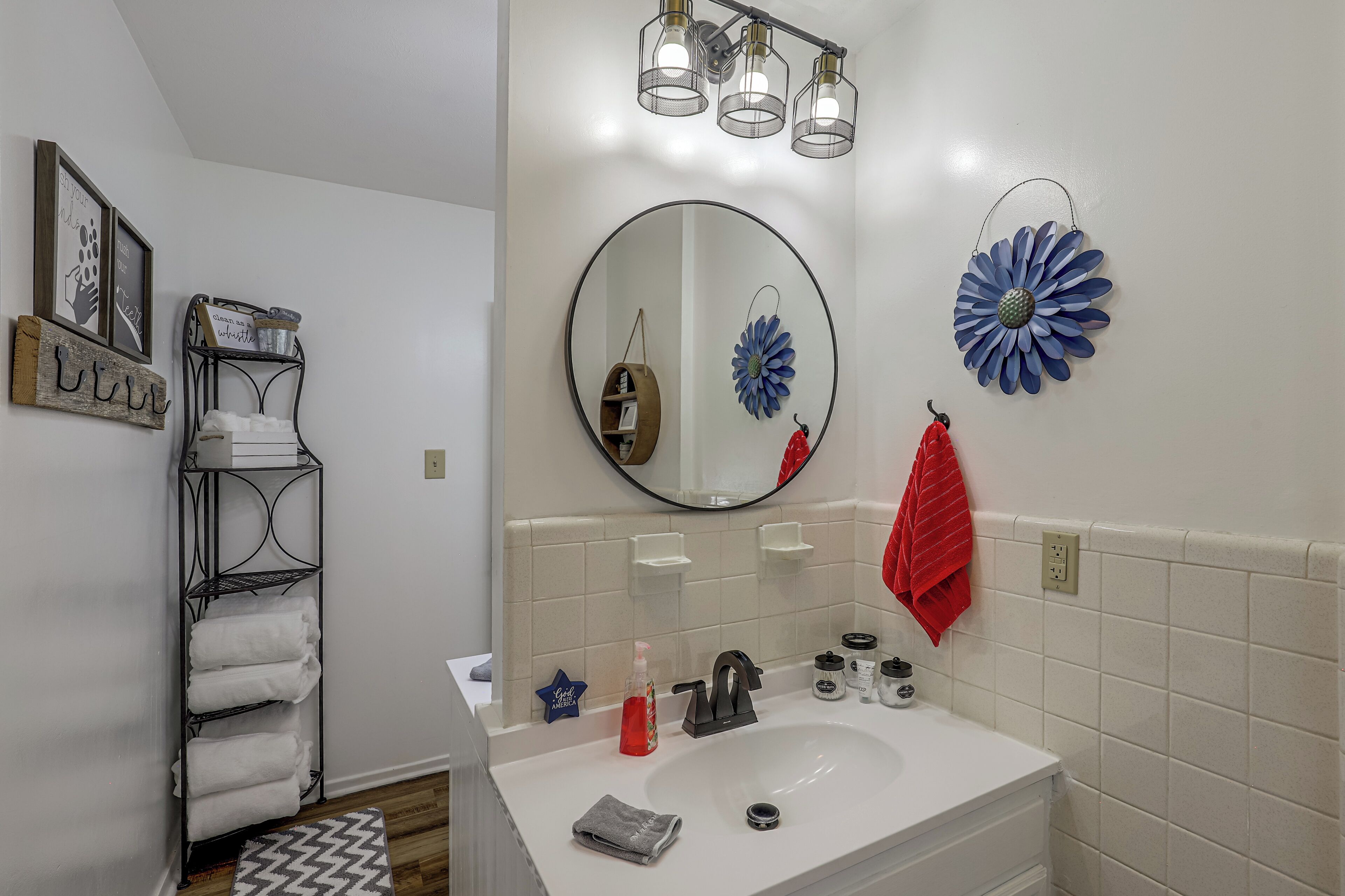 A bathroom with a white sink, a mirror, a towel rack, and a decorative flower.
