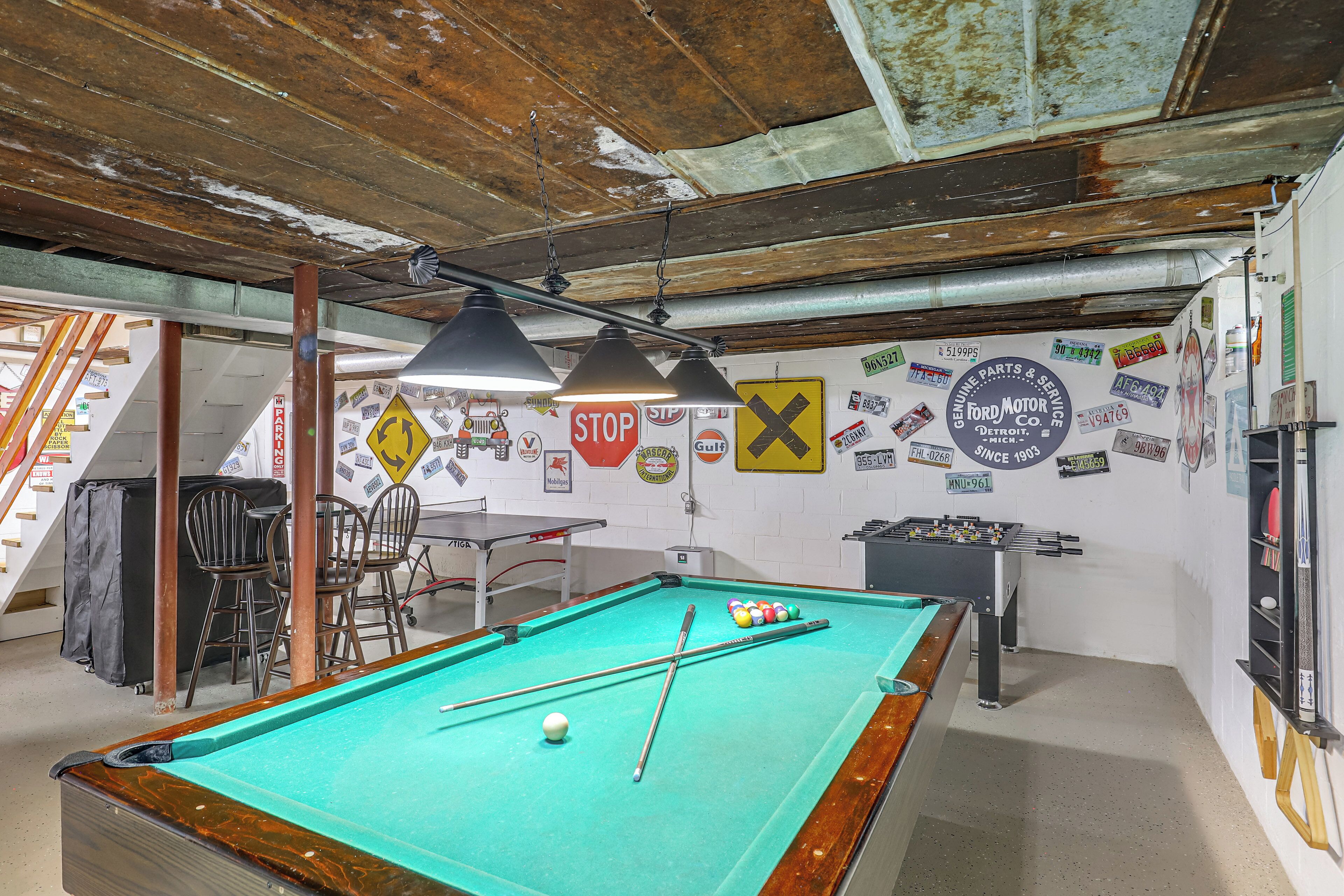 A pool table in a room with a rustic ceiling, various wall stickers, and a table with chairs.