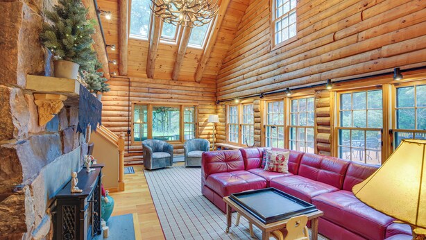 A log cabin interior with a red leather sofa, stone fireplace, and large windows. - Game Room w/ Speakeasy Saloon: Accord Retreat (Accord)