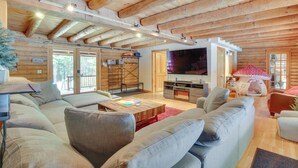A cozy log cabin interior with a living area featuring a large sofa, a coffee table, and a television. - Game Room w/ Speakeasy Saloon: Accord Retreat (Accord)
