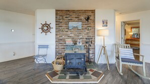 Un salon avec une cheminée en briques, un fauteuil à bascule, un canapé bleu et un plancher en bois.