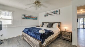 Une chambre avec un lit en bois, un ventilateur de plafond et des œuvres d’art accrochées aux murs.