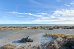 Una spiaggia con sabbia, dune e cielo sereno.