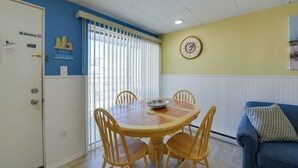 A dining area with a round table and four chairs, a blue couch, and a clock on the wall. - Updated Oceanside Condo - 5 Miles to Cape May! (Wildwood Crest)