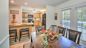 A dining area with a wooden table, chairs, and a kitchen in the background. - Fire Pit & Grill: Tranquil Retreat in Hot Springs (Hot Springs Village)