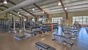 A spacious gym with various exercise equipment, large windows, and a high ceiling. - Fire Pit & Grill: Tranquil Retreat in Hot Springs (Hot Springs Village)