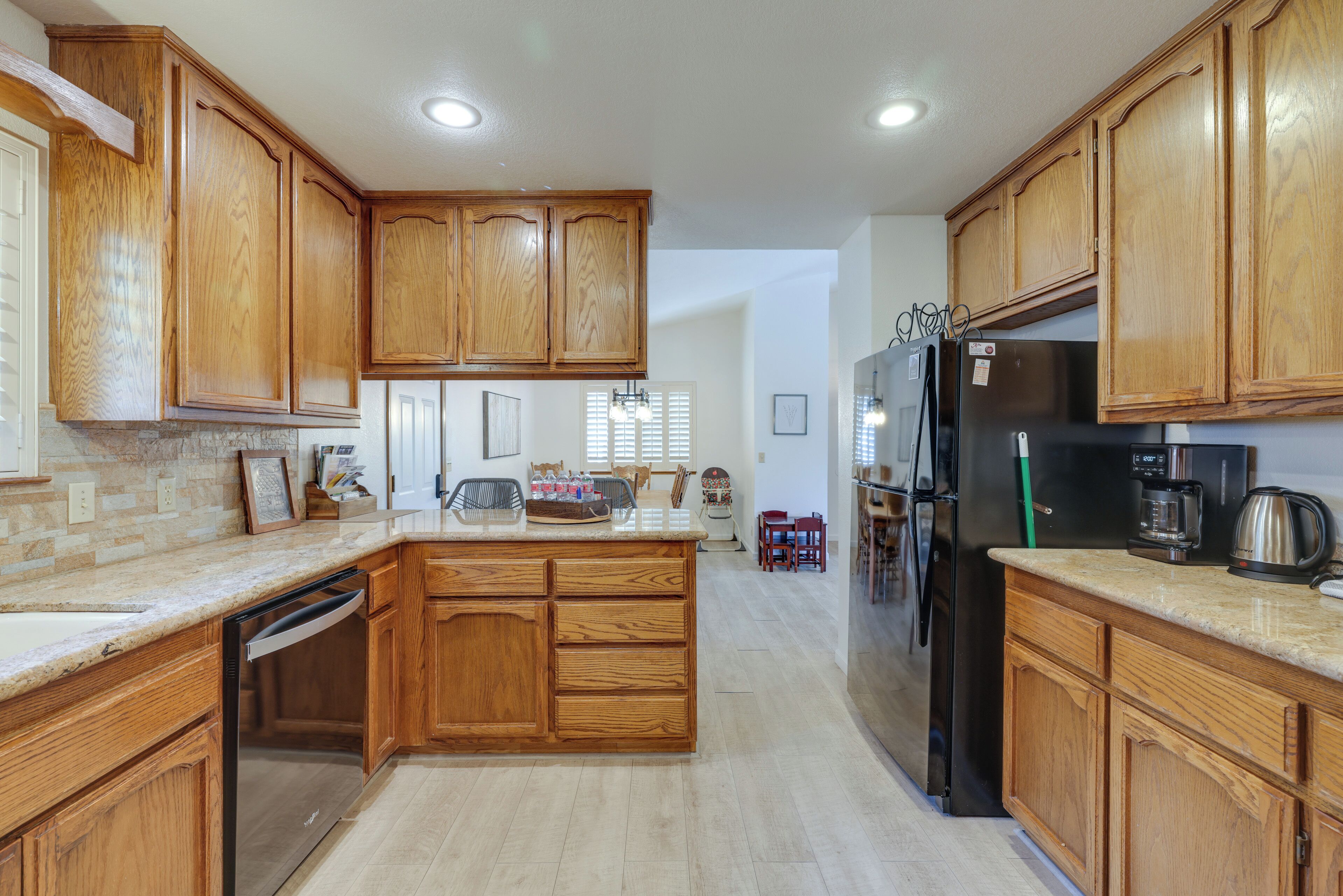 A kitchen with wooden cabinets, a black refrigerator, and a dishwasher.