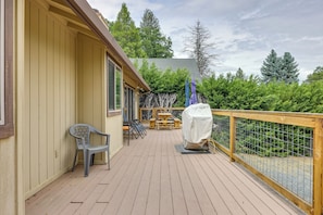 A wooden deck with a covered picnic table and chairs, a covered grill, and a view of the surrounding greenery. - Hikers Escape Home Near Beach, Golf & Yosemite (Groveland)