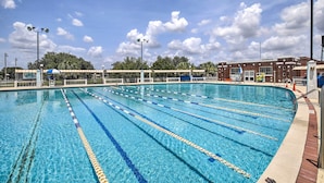 A swimming pool with clear lanes, surrounded by a fence and a building with a brick facade. - Walk to Parks & Dining! Updated Ybor City Home (Tampa)