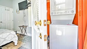 A bedroom with a bed, a television mounted on the wall, and a washing machine in the corner. - Walk to Parks & Dining! Updated Ybor City Home (Tampa)
