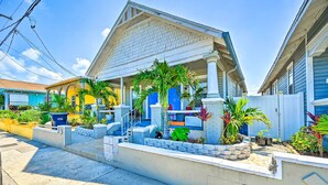 A two-story house with a porch, a blue door, and a small garden with palm trees. - Walk to Parks & Dining! Updated Ybor City Home (Tampa)