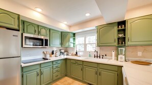 A kitchen with green cabinets, a stainless steel refrigerator, a microwave, and a sink. - < 4 Mi to Cooperstown: Charming Historic Home! (Fly Creek)