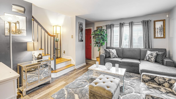 A modern living room with a staircase, grey sofa, and a coffee table. - Newark Home w/ Deck & Fire Pit, 16 Mi to Nyc! (Newark)