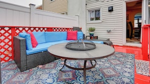 An outdoor patio with a blue sofa, a round table, and a patterned rug. - Newark Home w/ Deck & Fire Pit, 16 Mi to Nyc! (Newark)