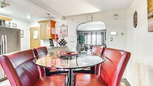 A dining area with a glass table surrounded by red leather chairs, a ceiling fan, and a kitchen in the background. - Newark Home w/ Deck & Fire Pit, 16 Mi to Nyc! (Newark)