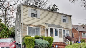 A two-story house with a garage, a front porch, and a small front yard with bushes. - Newark Home w/ Deck & Fire Pit, 16 Mi to Nyc! (Newark)