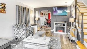 A modern living room with a patterned sofa, a marble coffee table, and a fireplace. - Newark Home w/ Deck & Fire Pit, 16 Mi to Nyc! (Newark)
