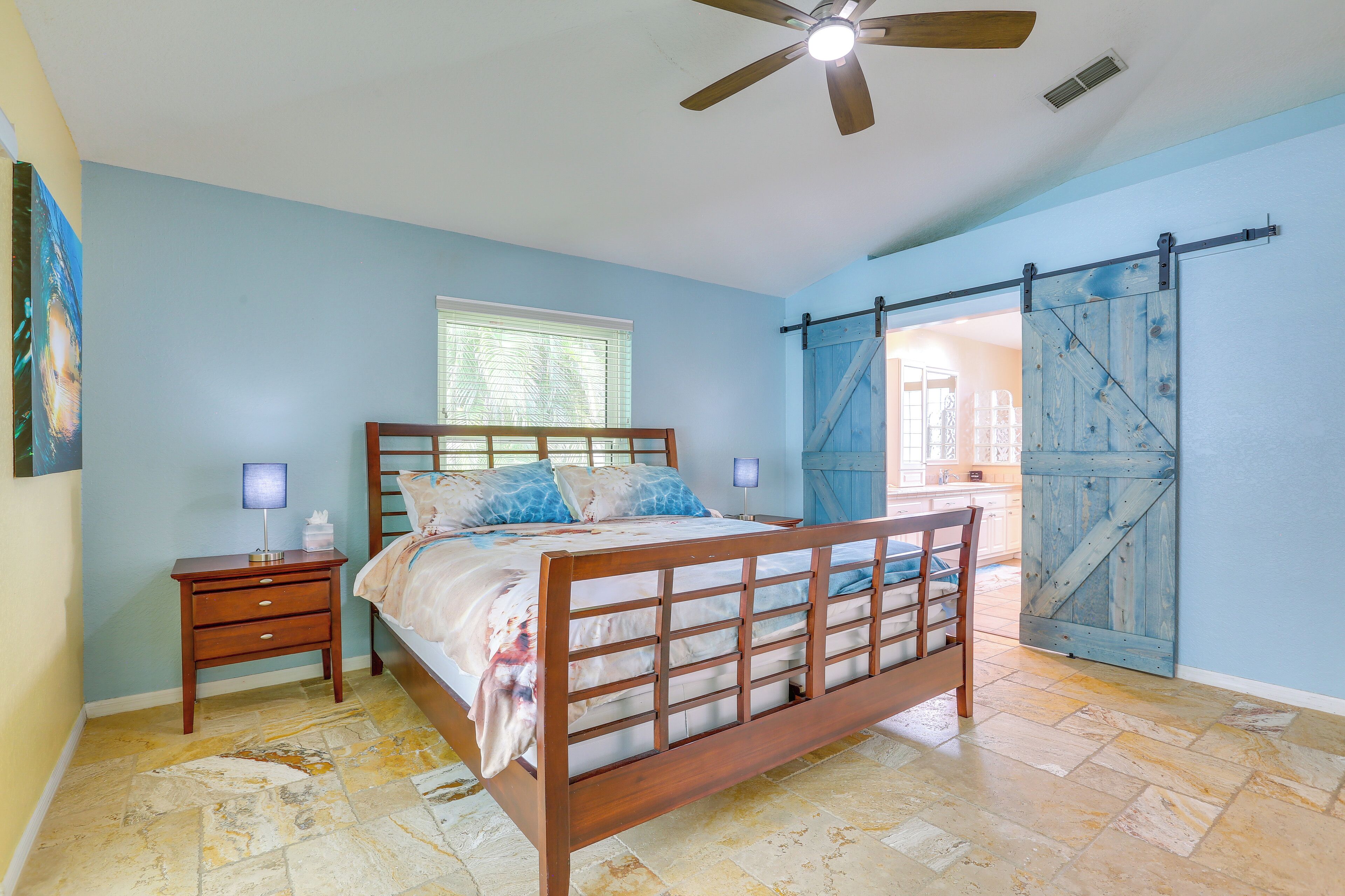A bedroom with a wooden bed, a nightstand, a ceiling fan, and a blue sliding barn door.