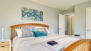 A neatly made bed with a headboard, a bedside table with a lamp, and a wall with a decorative pattern.