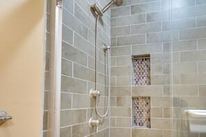 Un espace douche avec des carreaux gris et un panneau décoratif en mosaïque.