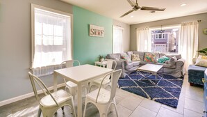 A living room with a dining table, chairs, a sofa, and a ceiling fan.