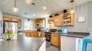 A modern kitchen with wooden cabinets, stainless steel appliances, a granite countertop, and pendant lighting.