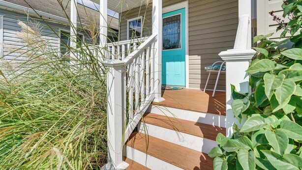 A house with a porch, a blue door, and a staircase leading to the front door.
