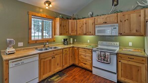 A kitchen with wooden cabinets, a built-in microwave, a dishwasher, and a stove. - Hungry Horse Cabin: Deck, Fire Pit, Near Glacier! (Hungry Horse)