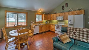 A cozy kitchen with wooden cabinets, a dining table with chairs, a refrigerator, and a ceiling fan. - Hungry Horse Cabin: Deck, Fire Pit, Near Glacier! (Hungry Horse)