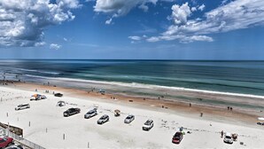 Ein Strand mit parkenden Autos und Menschen.