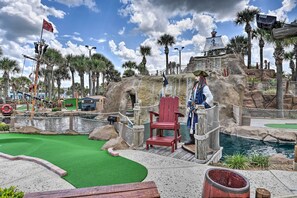 Play a round of golf amidst lush palm trees and a serene pond.