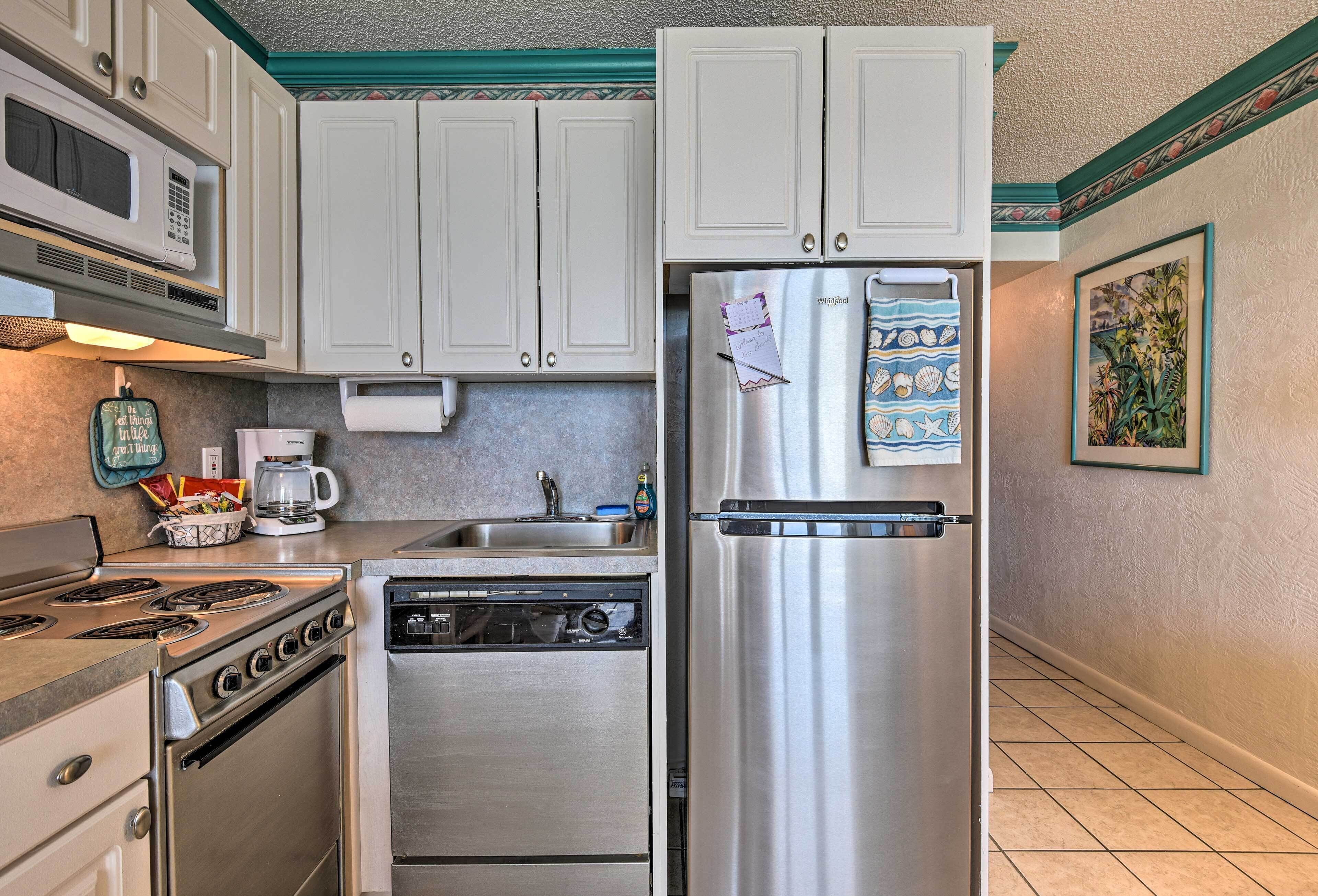 A compact kitchen with white cabinets, stainless steel appliances including a refrigerator, microwave, stove, and dishwasher.