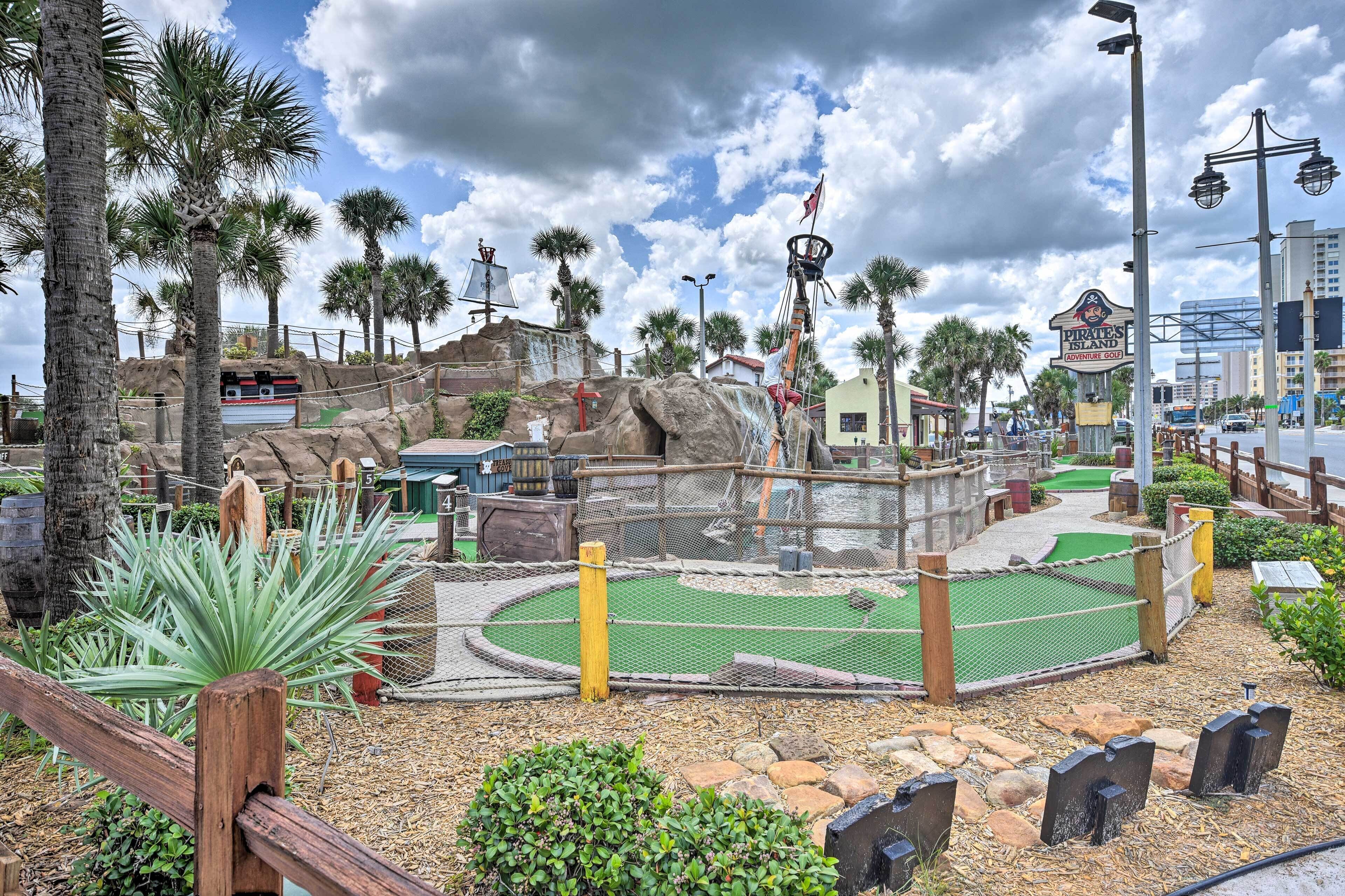 Un camp de mini-golf amb una illa rocosa, palmeres i un cartell que diu 'Pirate Island'.