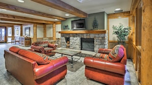 A spacious living area with leather sofas, a stone fireplace, and a television mounted above it. - Keystone Ski Condo w/ Mtn View - Walk to Gondola! (Keystone)