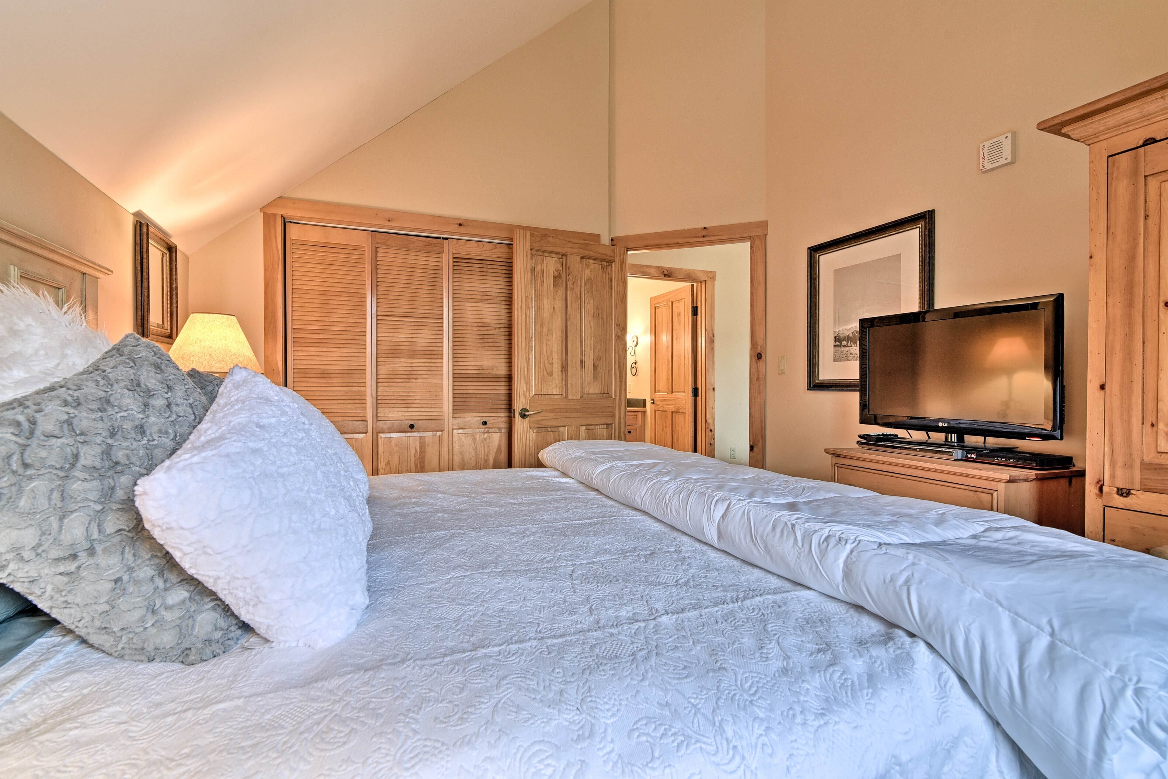 A bedroom with a bed, a television, and wooden wardrobes.