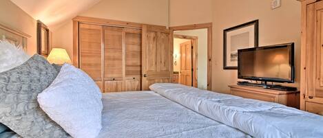 A bedroom with a bed, a television, and wooden wardrobes.