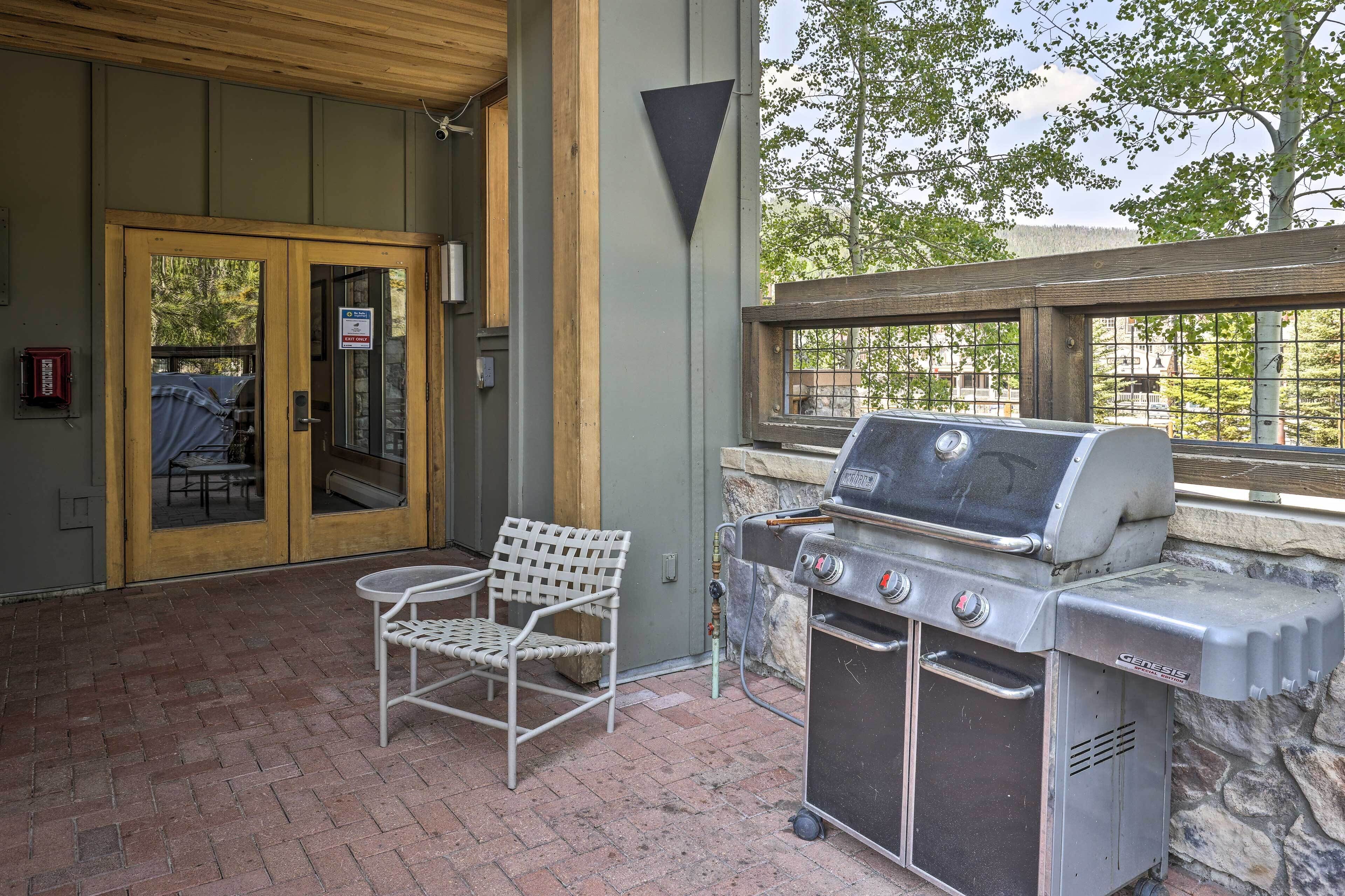 Un patio al aire libre con una parrilla, una silla y una mesa.