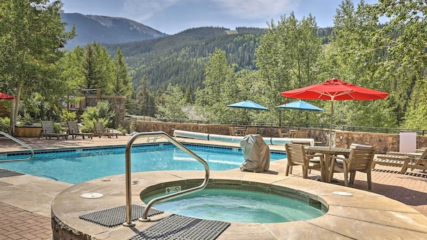 A pool area with a hot tub, lounge chairs, and umbrellas. - Keystone Ski Condo w/ Mtn View - Walk to Gondola! (Keystone)