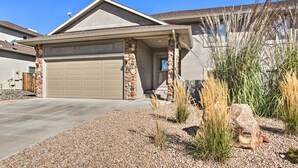 A house with a garage, stone pillars, and a gravel driveway.