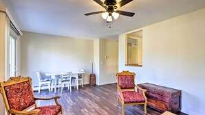 A spacious room with a ceiling fan, a dining area with a white table and chairs, and two ornate chairs with floral upholstery.
