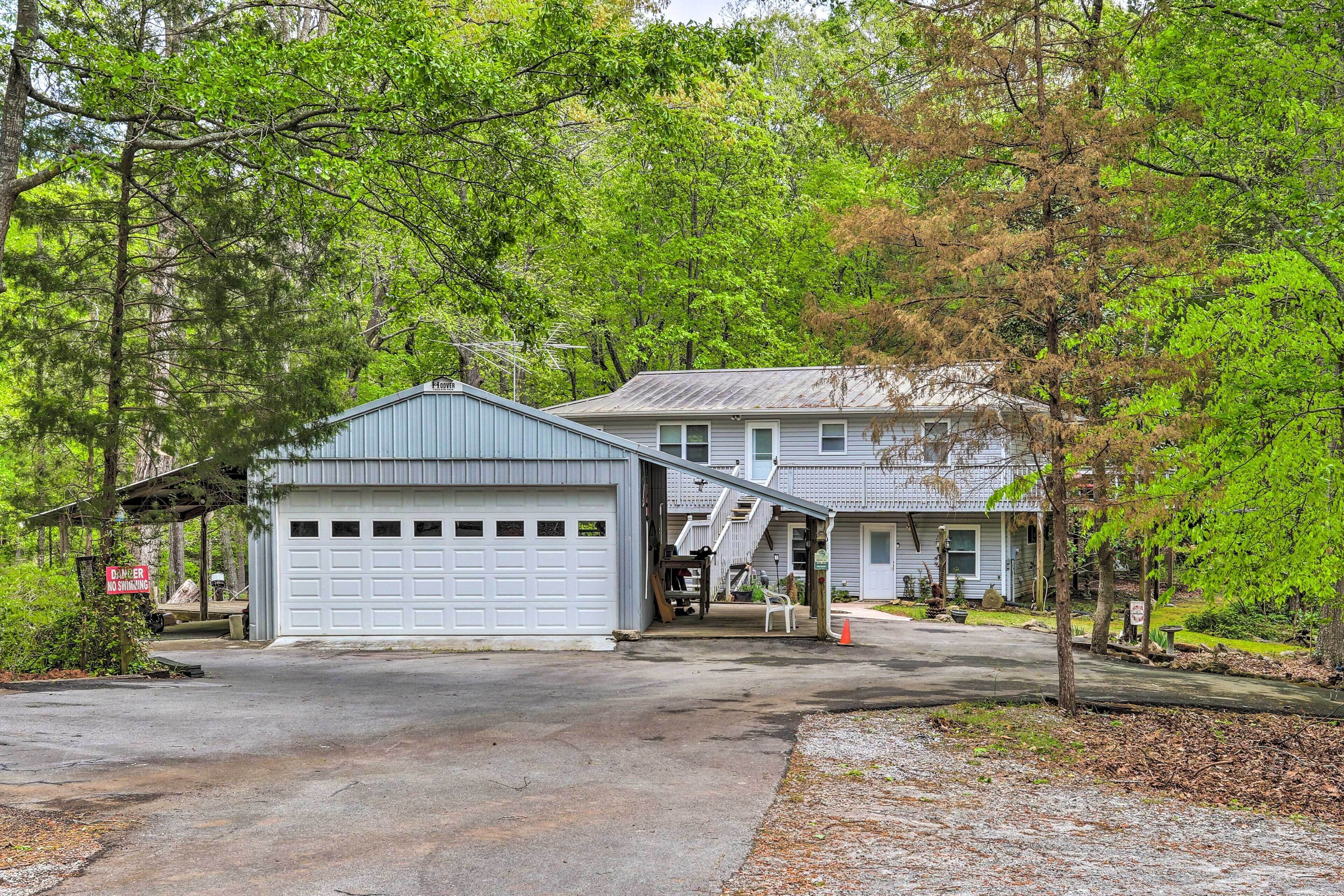 A two-story house with a garage, surrounded by trees.