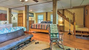 Une pièce spacieuse avec un grand lit, un fauteuil à bascule en bois, un canapé et un escalier.