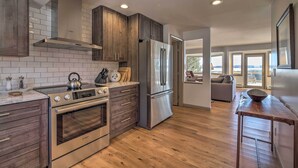 A modern kitchen with wooden cabinets, stainless steel appliances, and a view to the living area. - Plattsburgh Home w/ Deck on Lake Champlain (Plattsburgh)
