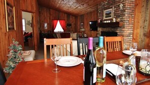 A wooden interior with a dining table set for two, a fireplace, and a Christmas tree. - South Londonderry Home, Walk to Magic Mtn Ski Area (Londonderry)