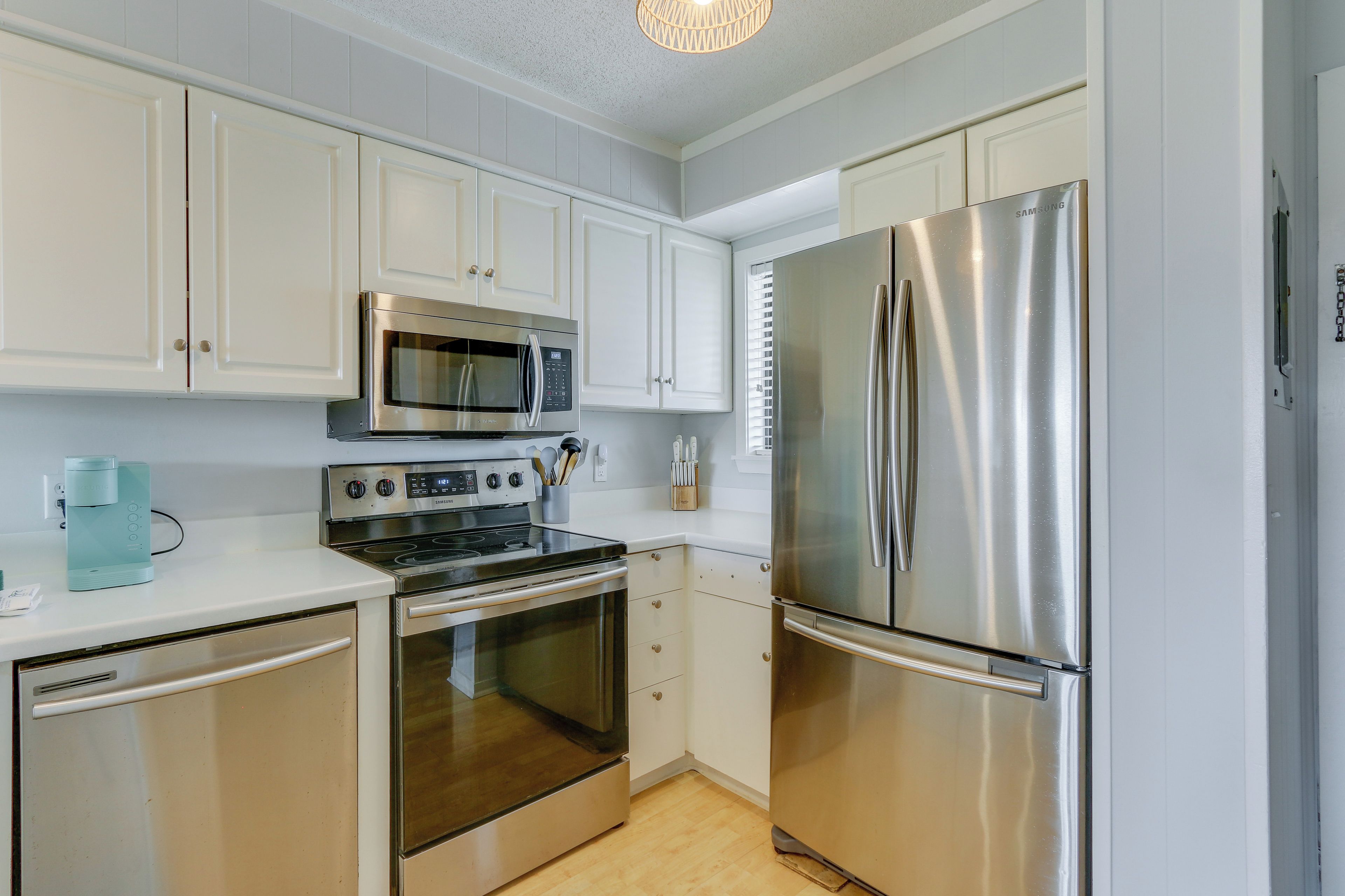 A modern kitchen with stainless steel appliances, white cabinetry, and a built-in oven.