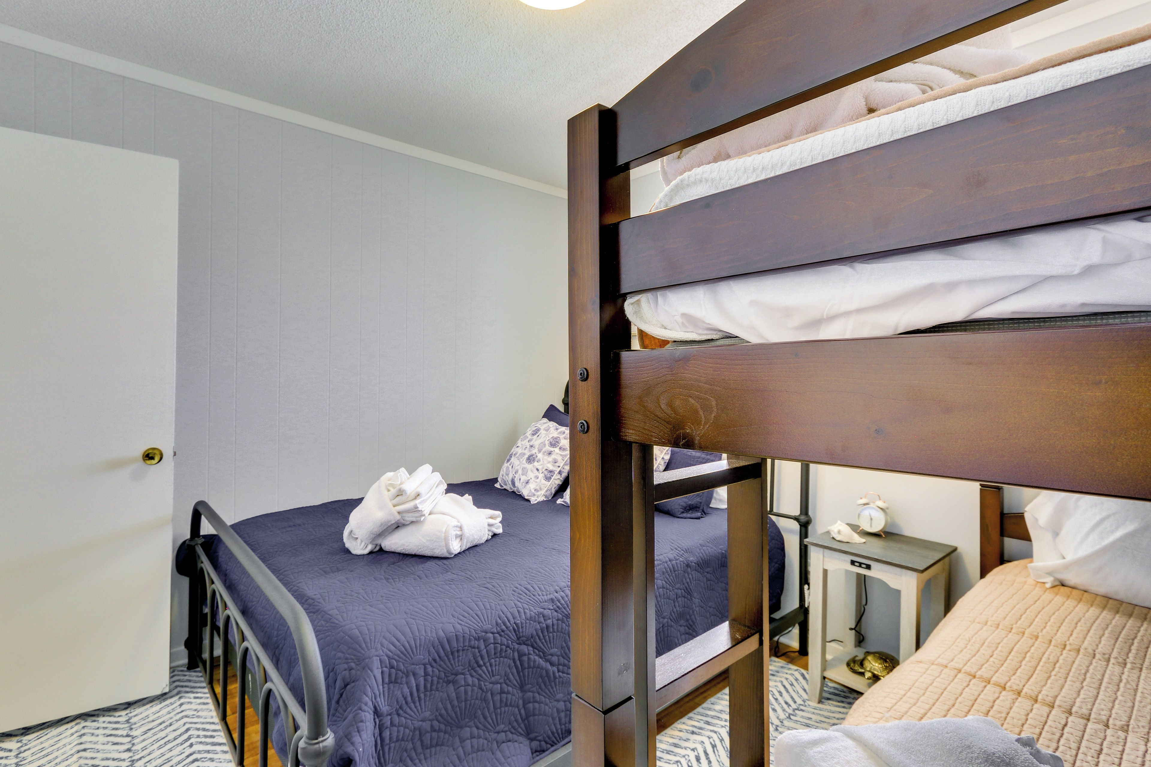 A bedroom with a bunk bed, a bedside table with a lamp, and a door.